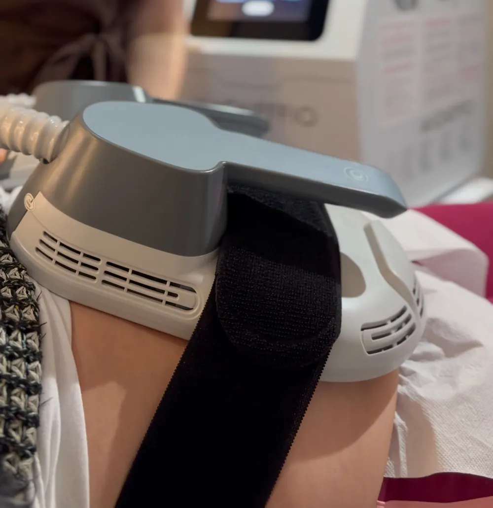 Aplikator Magneffio zapięty pasem na udzie klientki, w tle urządzenie Magneffio w gabinecie Przybylscy Clinic